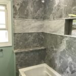 Custom bathroom features TYVARIAN SMOKE walls and grout free accents. Contact AMI in Canton, Ohio for a custom bathroom.