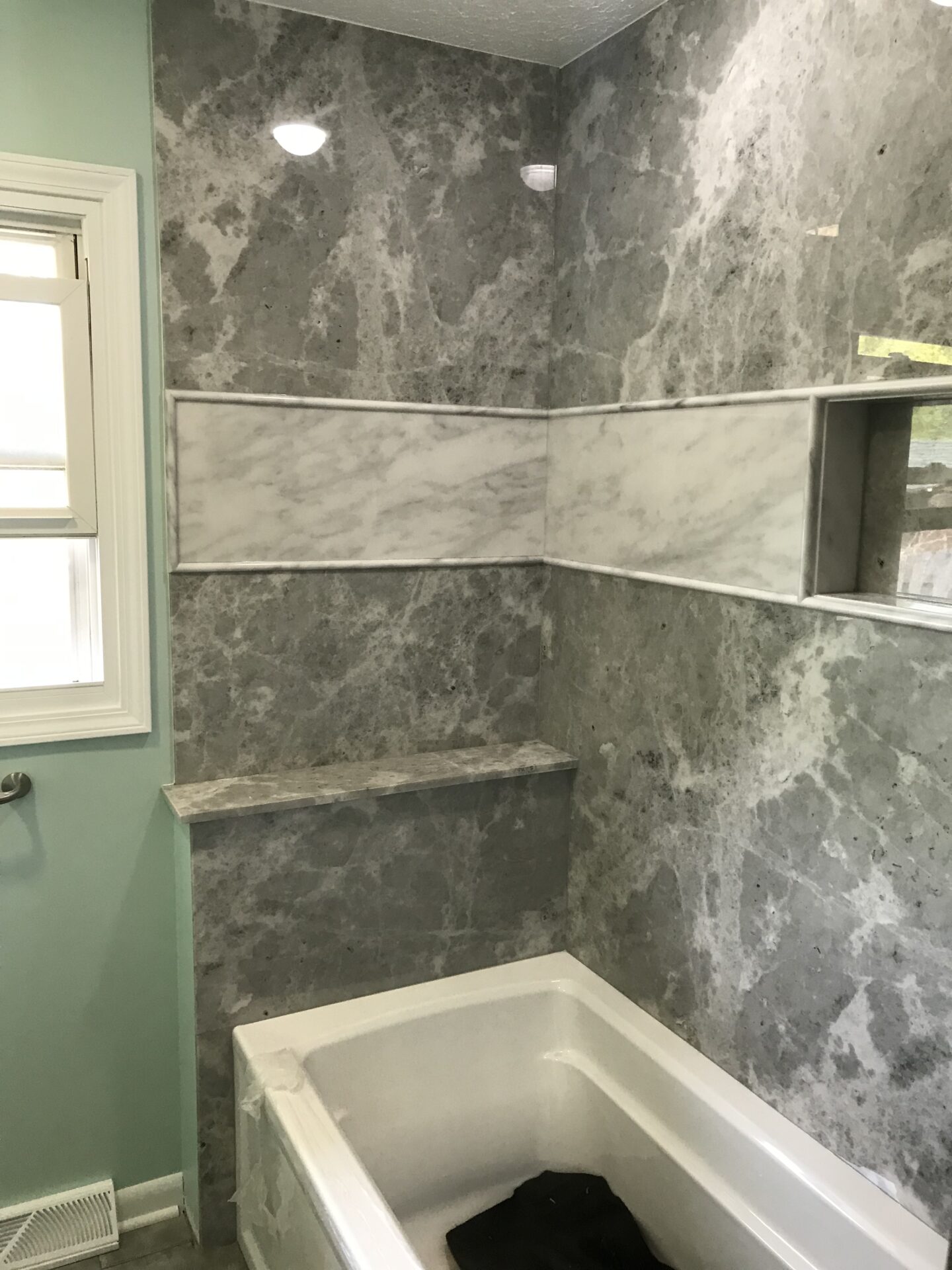 Custom bathroom features TYVARIAN SMOKE walls and grout free accents. Contact AMI in Canton, Ohio for a custom bathroom.