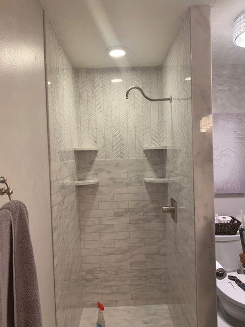TYVARIAN STATUARY GRAY TILE with herringbone accents. Contact AMI in Canton, Ohio to customize your bathroom with no leak grout free tile alternatives.
