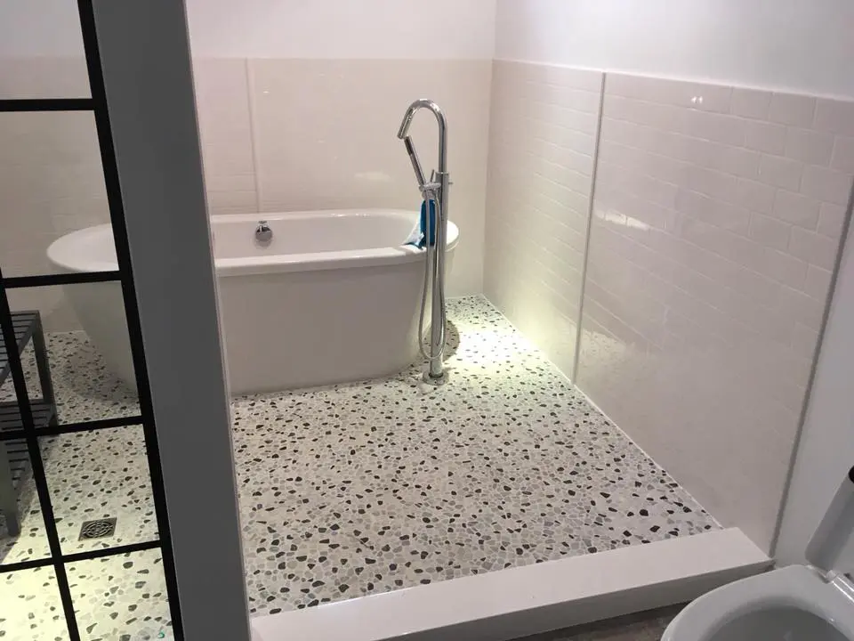 A White Bathroom Floor With Black Mossiac Pieces